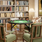 Round poker table with green felt top and black metal legs in living room