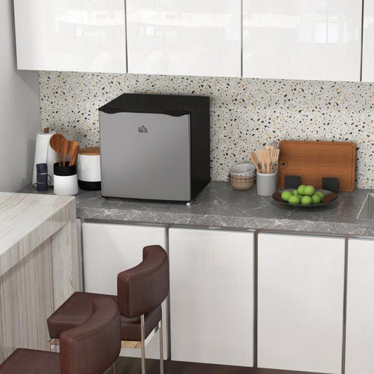 Mini upright freezer with door closed on a kitchen counter, white cabinet and black top
