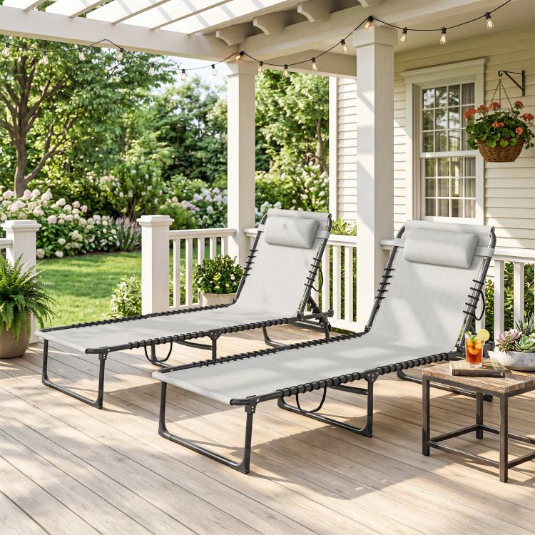 Outdoor pair of folding chaise lounge chairs with gray fabric, black frame, head pillows