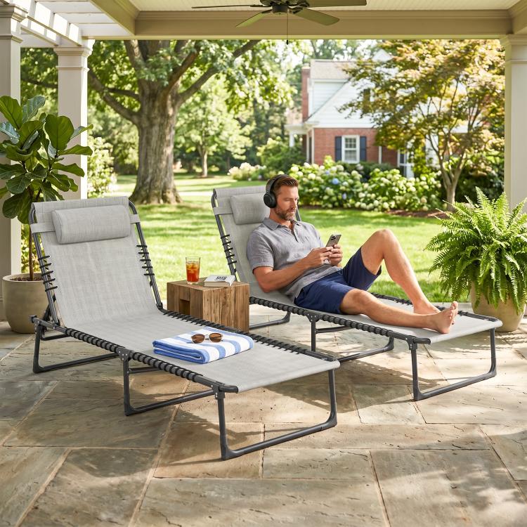 Reclining chaise lounge chair with gray cushions and black bungee straps on patio