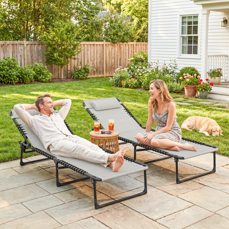 Pair of folding chaise lounge chairs with gray cushions and black bungee seating, reclined