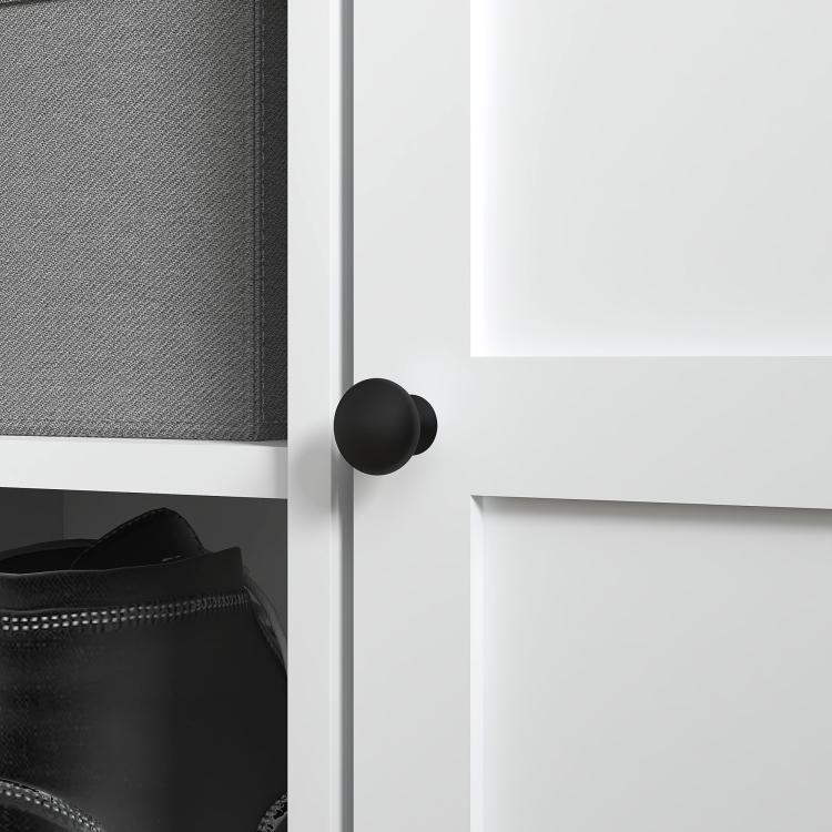 Close-up of black knob handle on white cabinet door of shoe storage bench