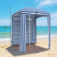 Blue-and-white striped cabana umbrella with walls and open entrance on sandy beach