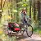 Black and red two-seat bike trailer with see-through mesh windows and safety flags
