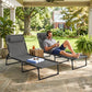 Gray folding chaise lounge chairs on patio with padded headrests and black frames