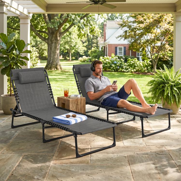 Gray folding chaise lounge chairs on patio with padded headrests and black frames