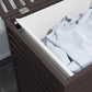 Dark brown bamboo laundry hamper with slatted sides and open top holding light cloth