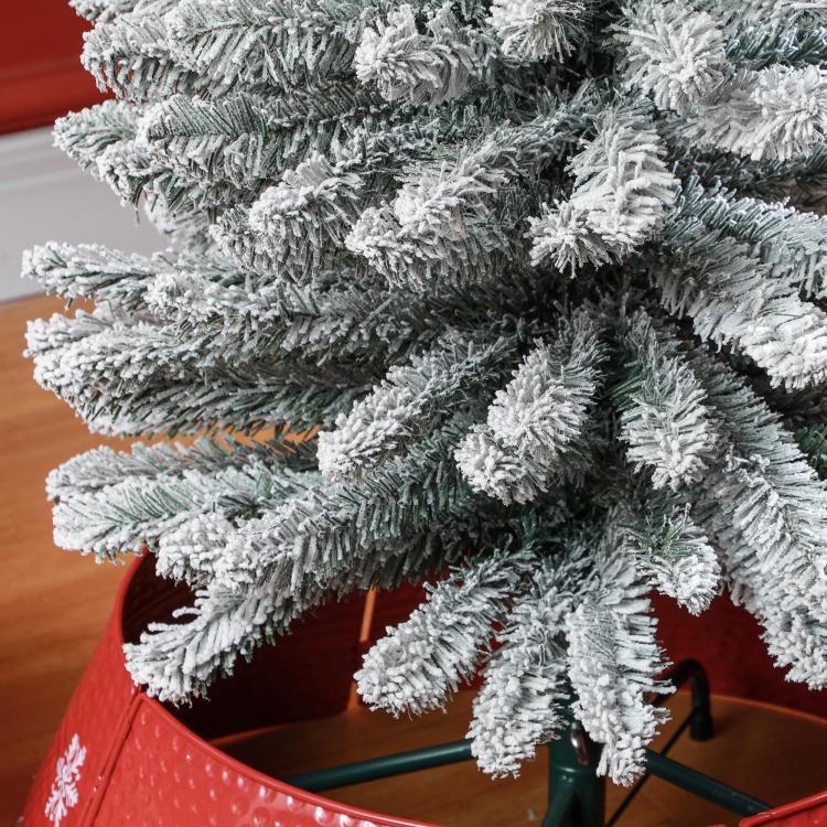 Snow-frosted artificial Christmas tree branches on metal stand frame