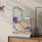 Light blue hamster cage with white wire walls and colorful play tubes on a tabletop