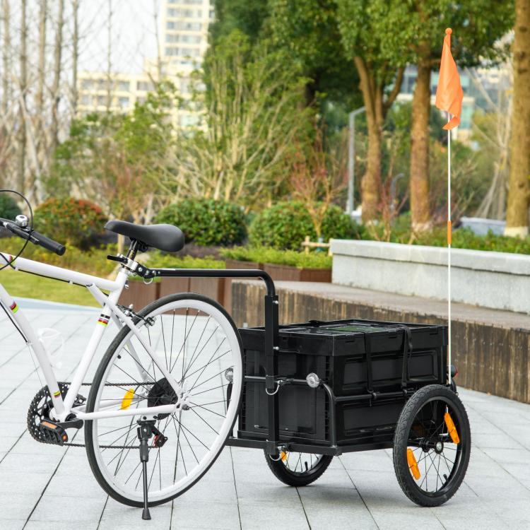 Bicycle cargo trailer beside parked bike, black rear cargo box with orange wheels