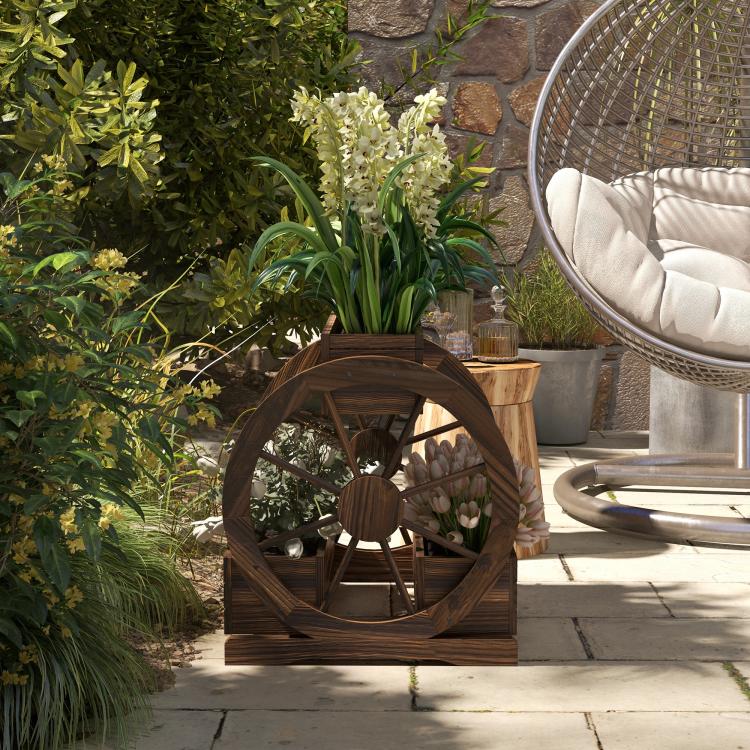 Wooden wagon planter box with wheel frame, holding green plants outdoors on patio