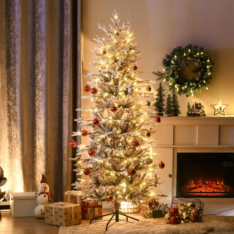 Lit artificial Christmas tree with snow-dusted branches and red ornament accents