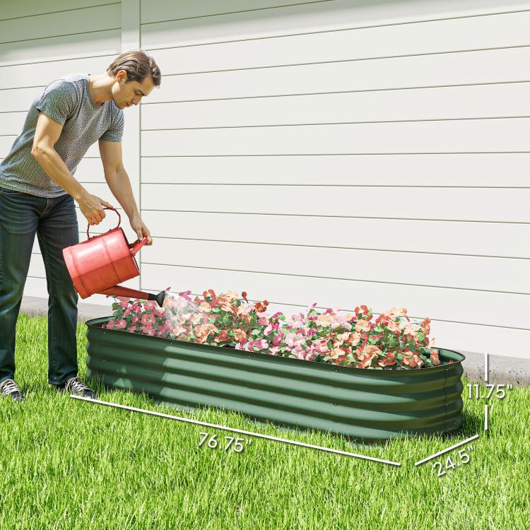 Green metal raised garden bed planter on grass with fresh soil and a watering pour
