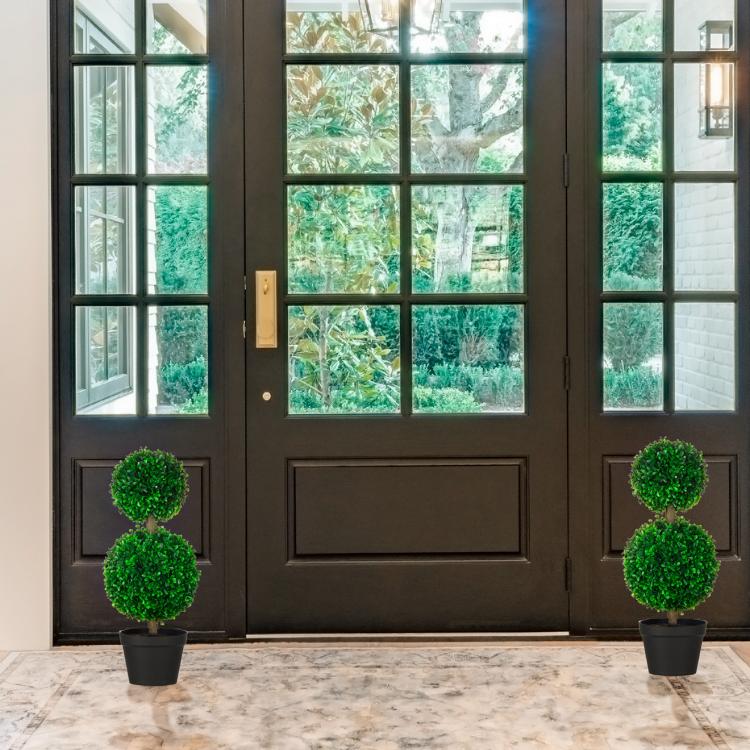 Artificial boxwood ball topiary trees in black pots with green pom-pom foliage at entry