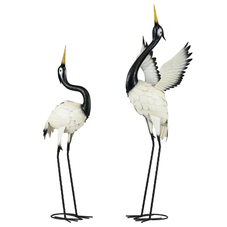 Set of 2 white heron sculptures with black heads and yellow beaks, standing on metal legs