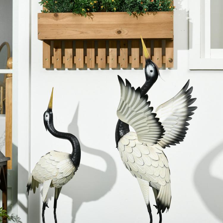 Two standing heron garden sculptures with black necks and white feathered wings