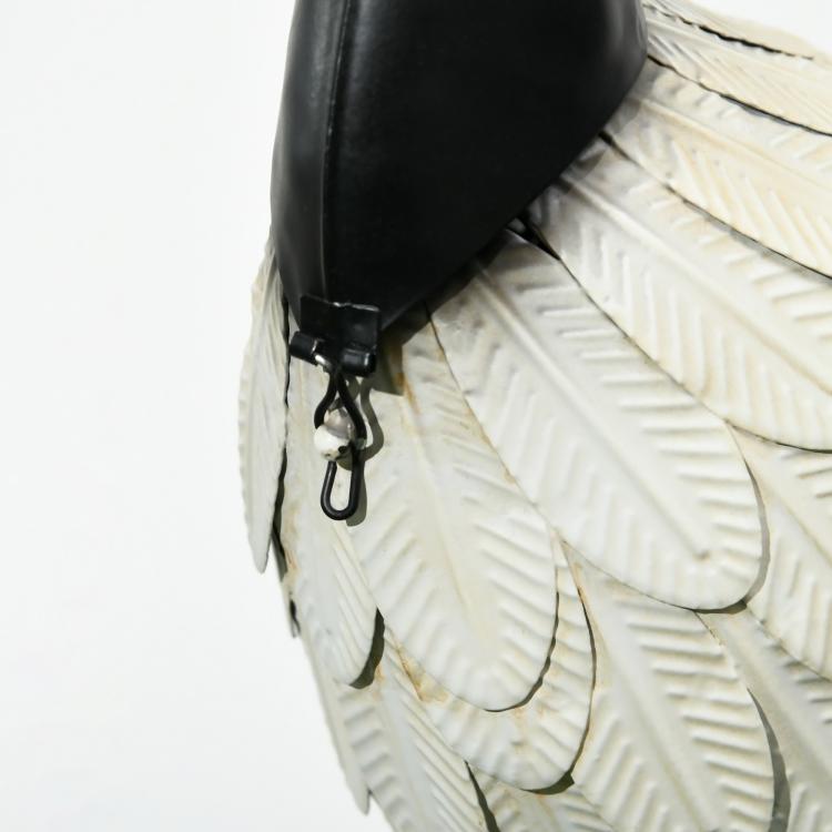 Close-up of white feathered heron sculpture with black metal attachment near legs