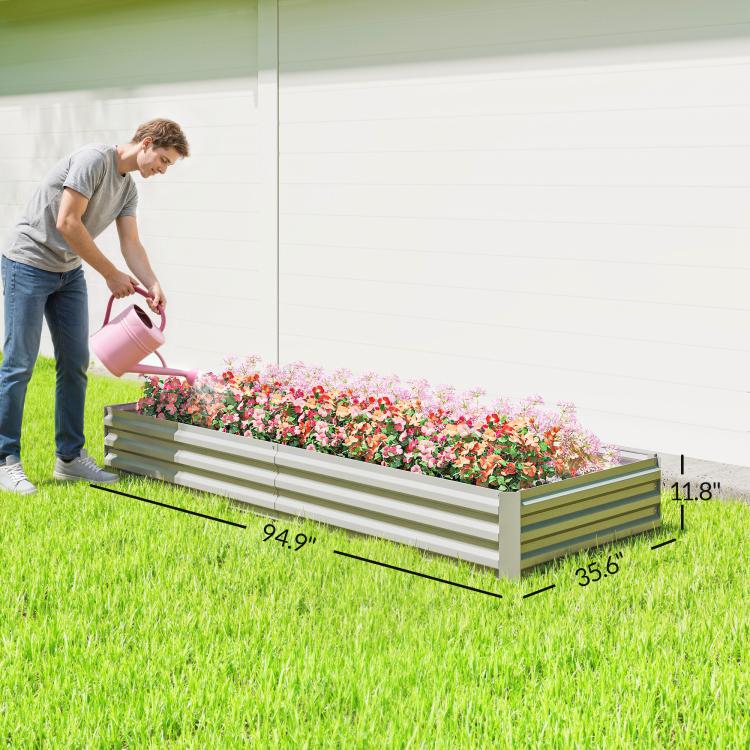 Silver galvanized raised garden bed planter on grass with flowers and watering