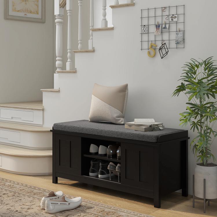 Black shoe storage bench with gray cushion and open shelves holding shoes
