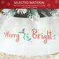 Cream white metal tree skirt close-up with “Merry & Bright” colorful lettering
