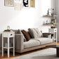 White 2-tier side table set beside a sofa, each with drawer and open shelf compartments.