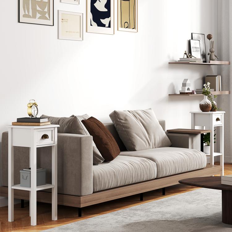 White 2-tier side table set beside a sofa, each with drawer and open shelf compartments.