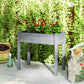 Raised dark gray planter box on four legs, filled with leafy plants