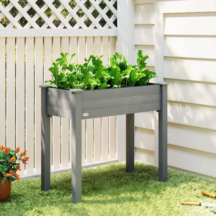 Elevated dark gray wooden planter box with four legs, filled with green herbs