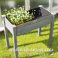 Dark gray raised wooden planter box with white blooms, four legs, open top