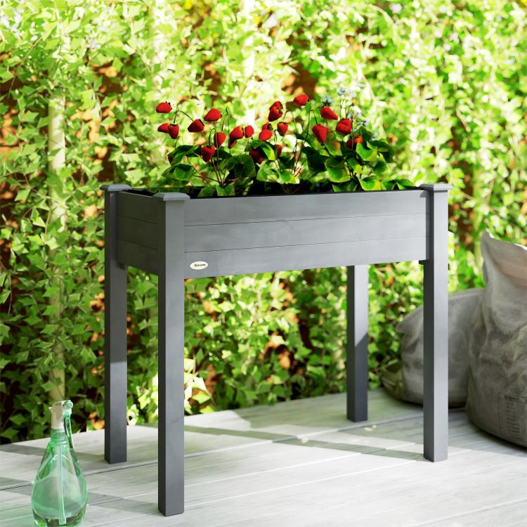 Raised dark gray wooden planter box on four legs, filled with red and green plants