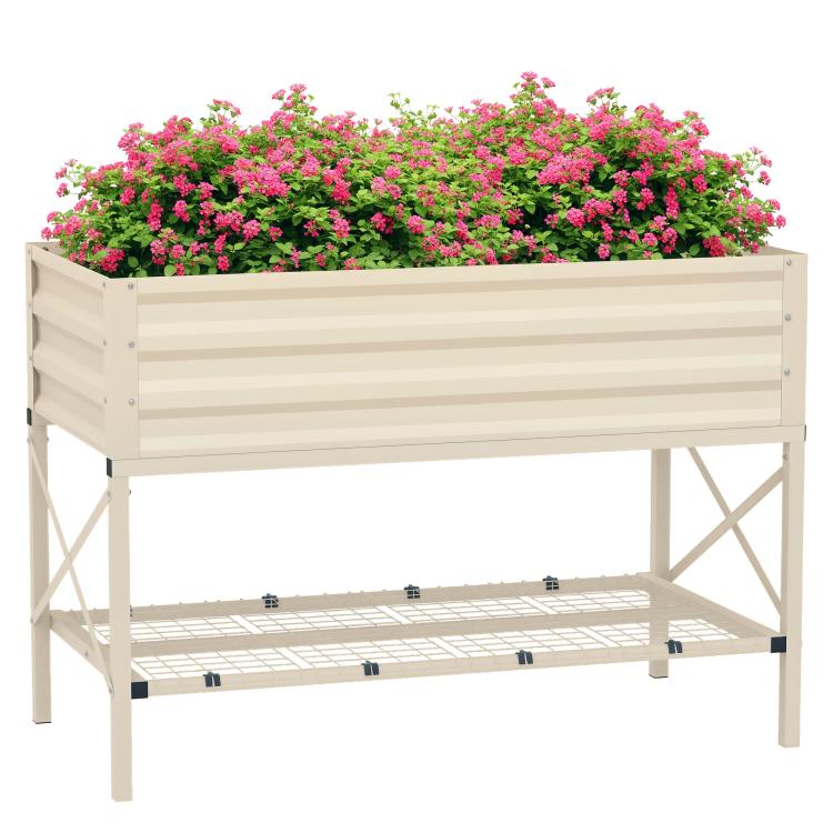 Cream metal raised garden bed with legs and bottom grid shelf, filled with pink flowers