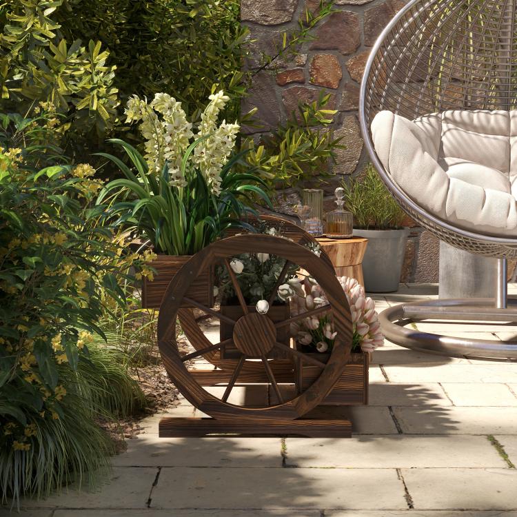 Wooden wagon planter box with wheel design, filled with pale flowers on a patio