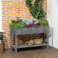 Dark gray raised garden bed with leafy plants and lower storage shelf on legs