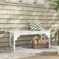 White slatted wooden garden bench with curved apron and pillow on the seat