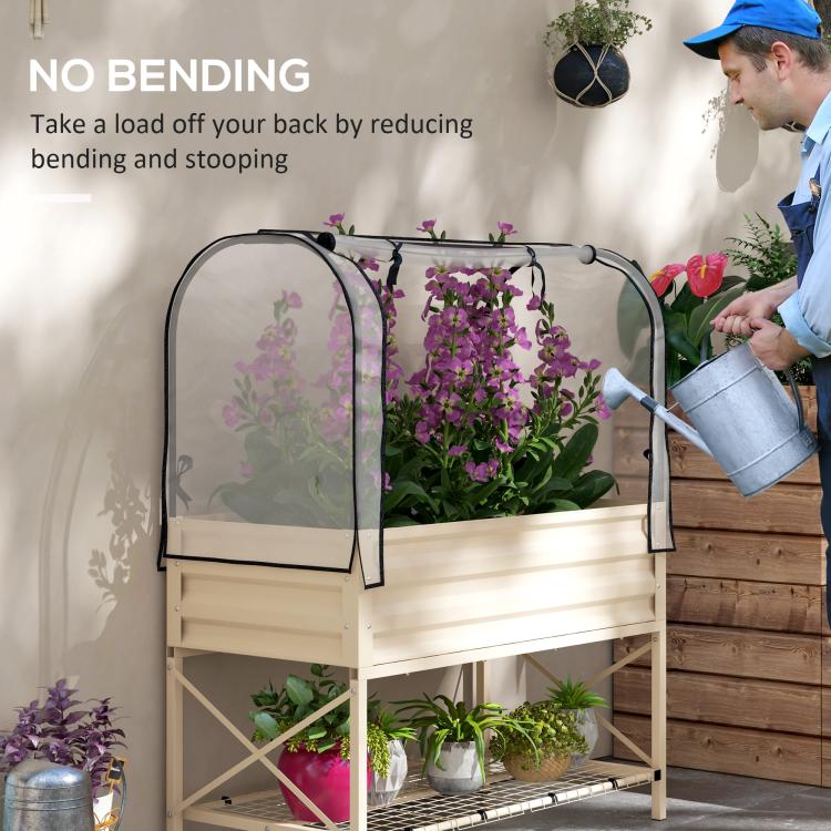 Raised garden bed with clear cover, cream frame, and gardener watering plants