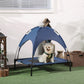 Dark blue elevated dog cot with UV canopy shade and black frame on indoor floor