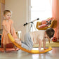 Orange wobble balance board on the floor with kids leaning forward for balance