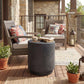 Cylindrical dark gray outdoor side table with concrete-look finish in patio setting