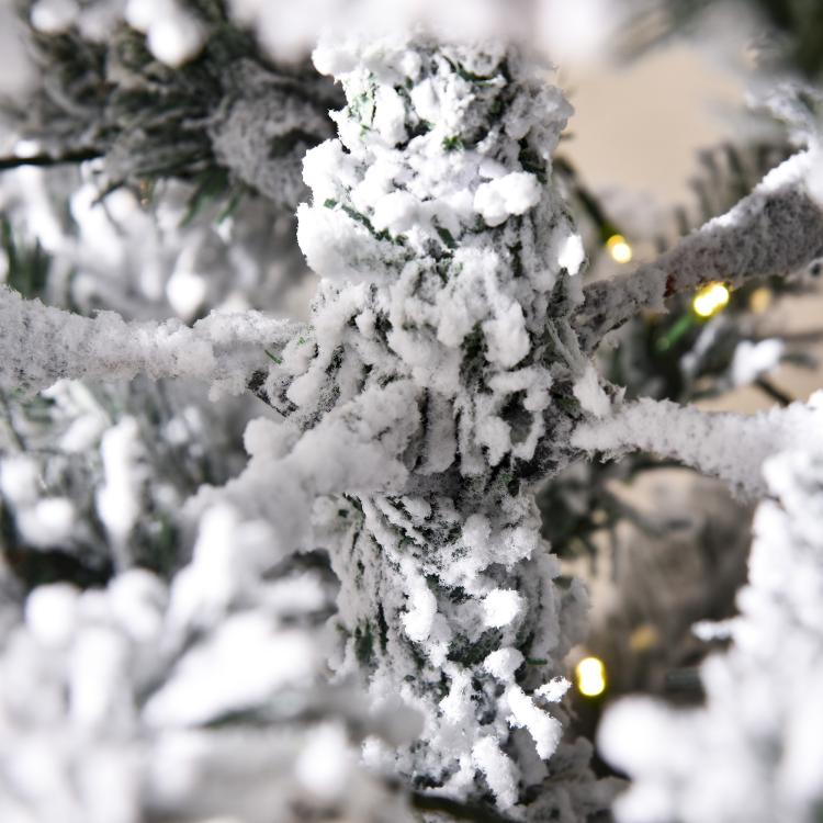 Snow-frosted fir branches with warm LED lights, close-up