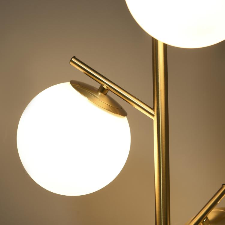 Close-up gold arm holding a white globe glass shade