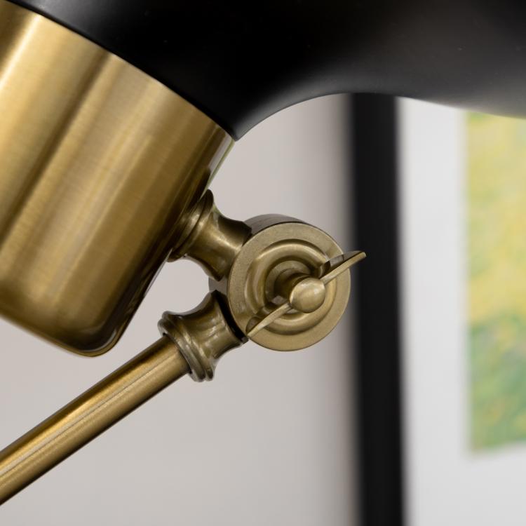 Gold swivel joint detail on black-and-gold adjustable floor lamp arm