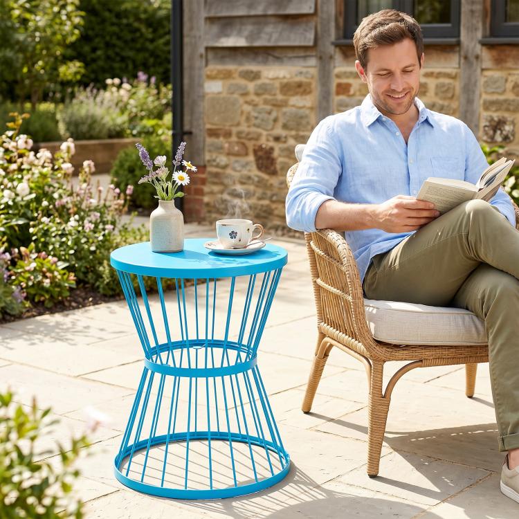 Blue hourglass side table with round top holding a coffee cup