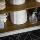 Lower shelf inside bathroom sink cabinet with cleaning bottles and pump dispenser
