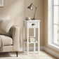 White narrow side table with drawer and shelf beside sofa, gold-toned drawer handle