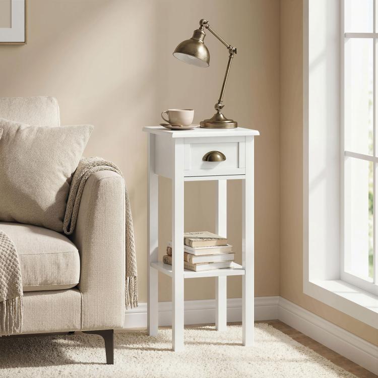White narrow side table with drawer and shelf beside sofa, gold-toned drawer handle