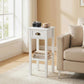 White side table with drawer and open shelf, brass-toned handle next to sofa