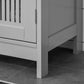 Close-up of grey cabinet side panel, hinges, and lower base leg on bathroom floor.