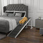 Foldable pet ramp with dark carpet grip surface and white frame beside bed