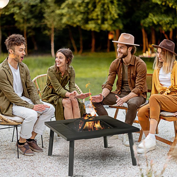 Black metal outdoor fire pit with spark screen and flames in center