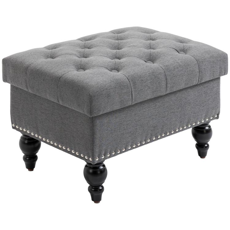 Gray storage ottoman with tufted seat, studded side trim, and turned wooden legs
